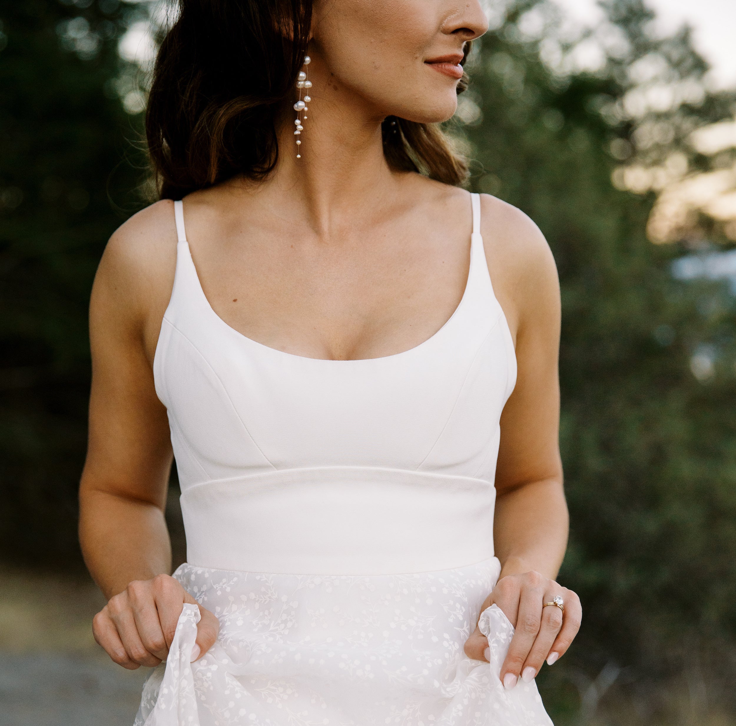 photo du buste d'une jeune mariée montrant sa robe blanche ainsi que ces accessoires de mariage en perles naturelles