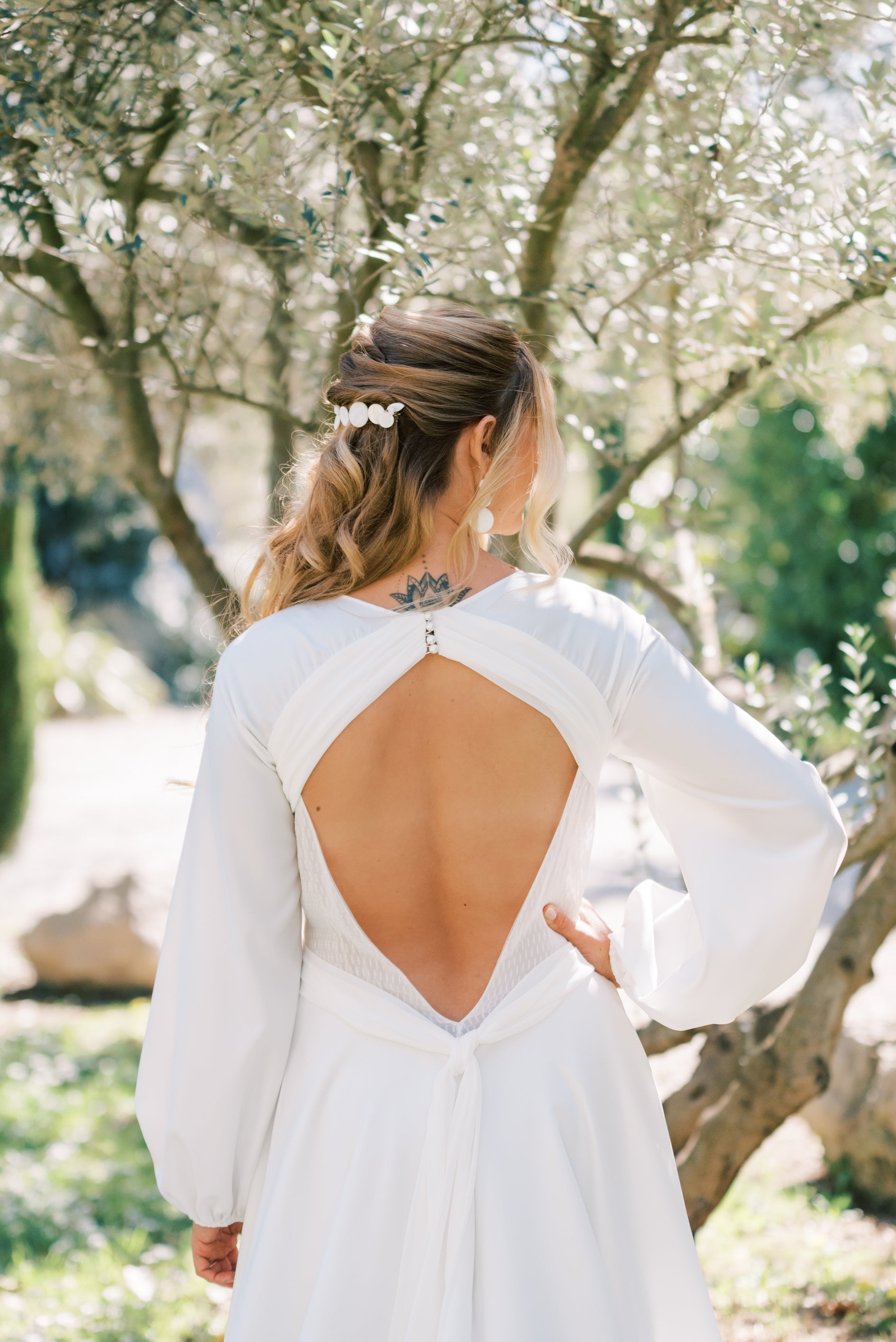 Femme pendant son mariage de dos montrant sa tenue de mariage et ses accessoires pour mariée notamment sa barrette en nacre