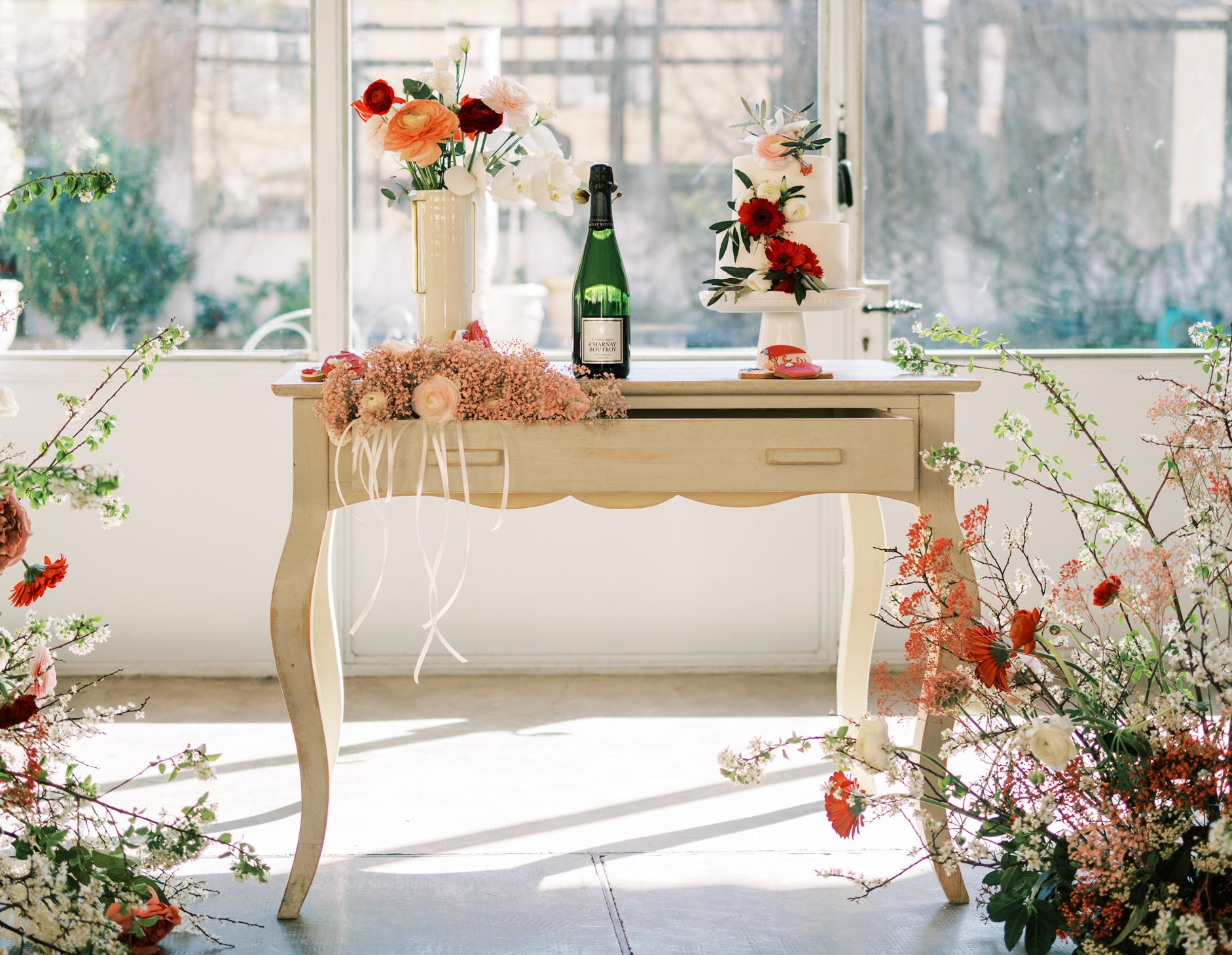 Table avec le gâteau du mariage ainsi que le champagne et des bouquets de fleurs