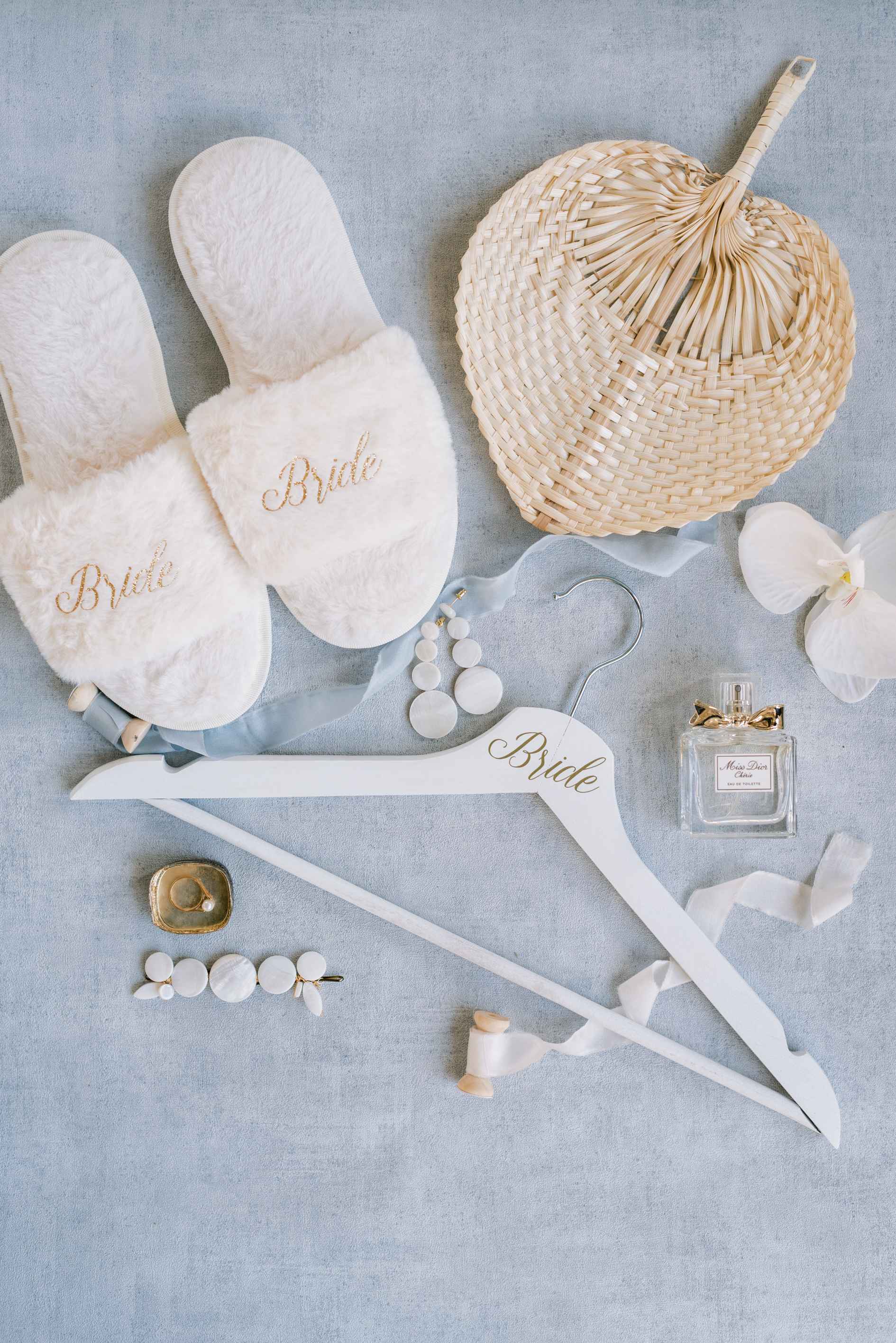 Photo des accessoires de la mariée avec ses bijoux de mariage en nacre mais aussi son parfum et ses pantoufles