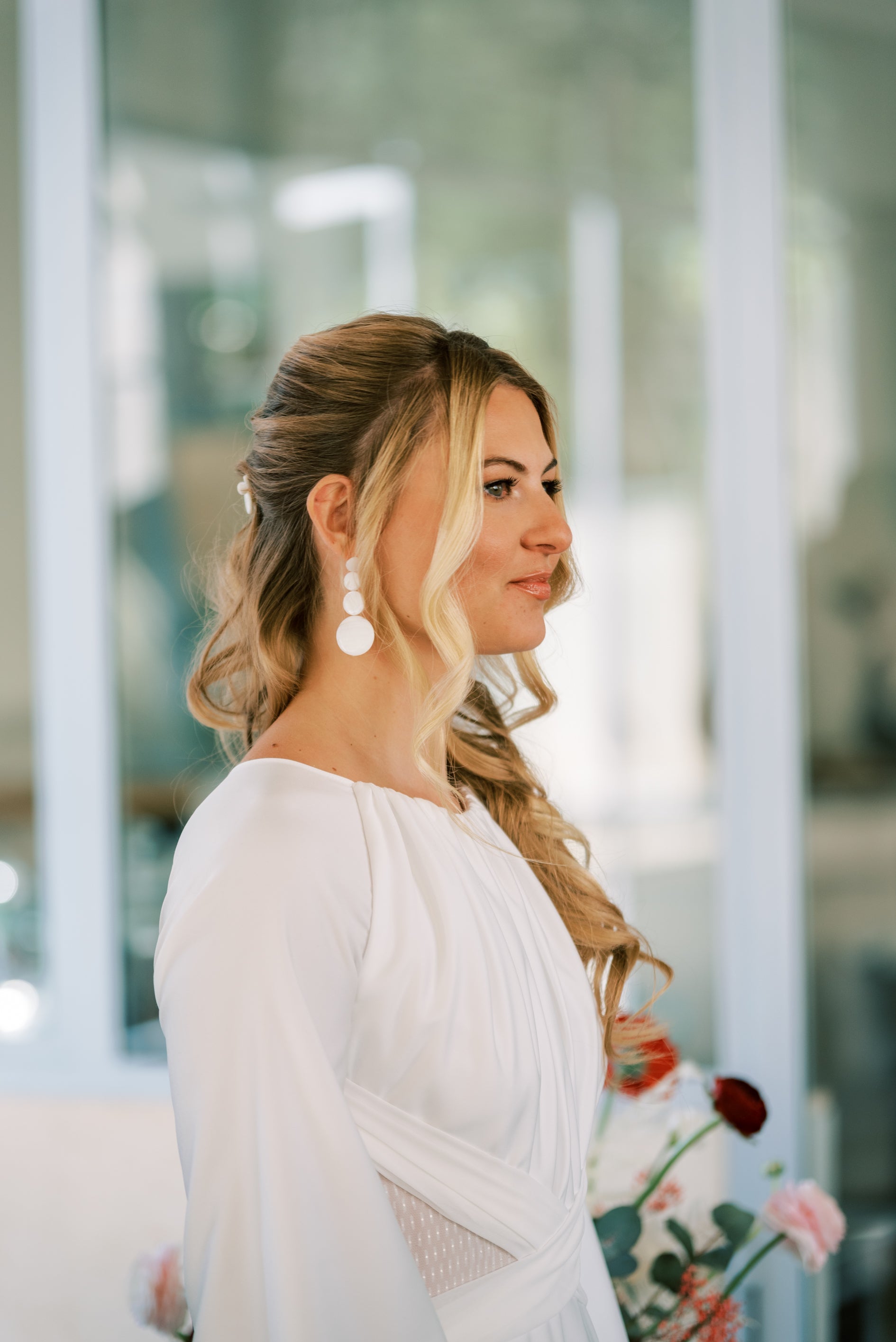 Jeune mariée de profil portant une tenue de mariage et montrant ces boucles d'oreilles pour les cérémonies 