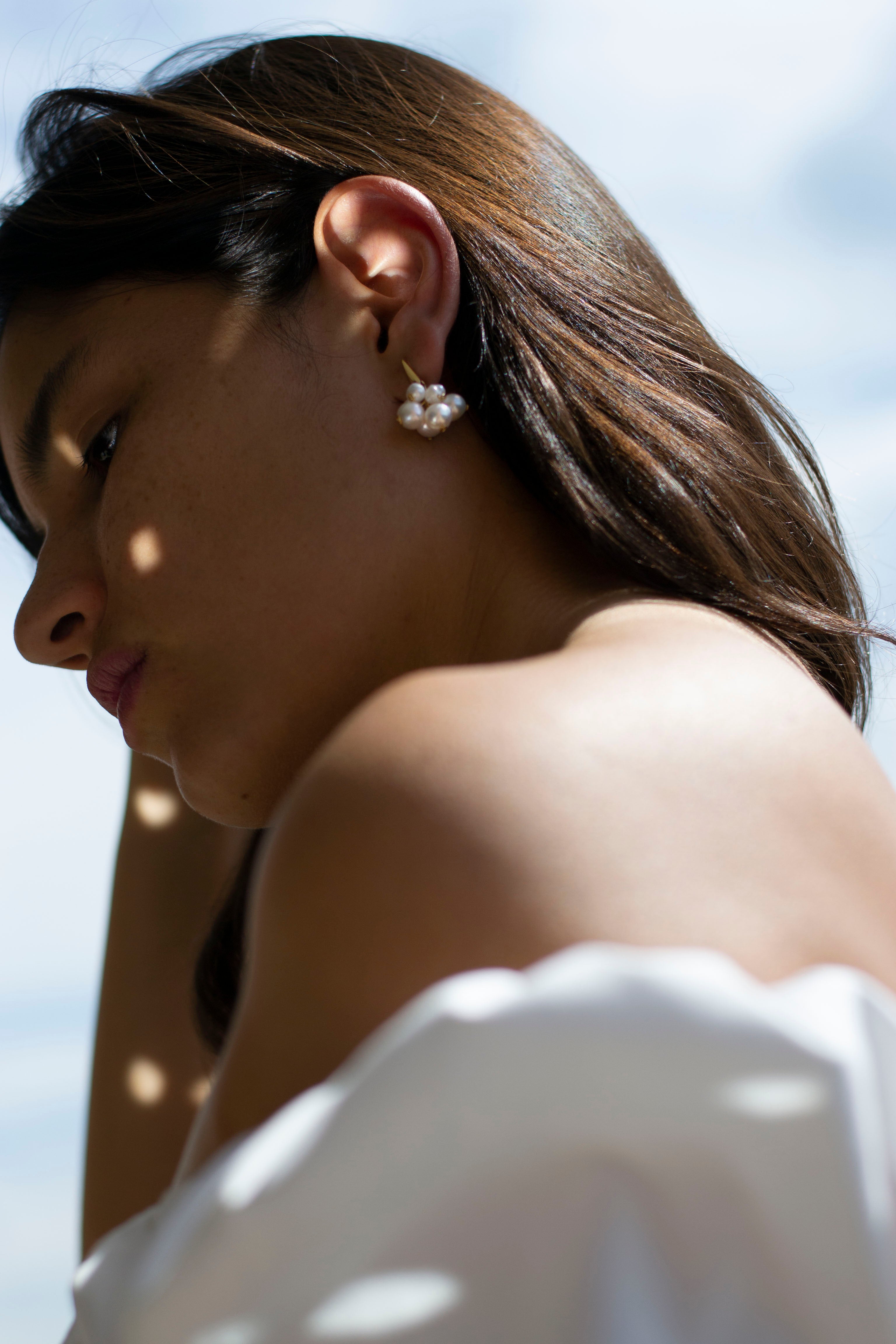 Mariée portant des boucles d'oreilles dorées avec bouquet de perles naturelles blanches